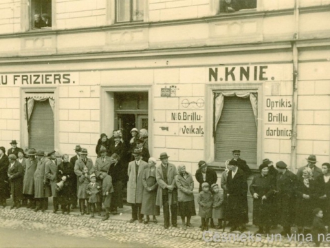 Cēsnieki sapulcējušies uz ietves pie nama Cēsīs, Rīgas ielā 6, ap 1930. - 1935. gadu.